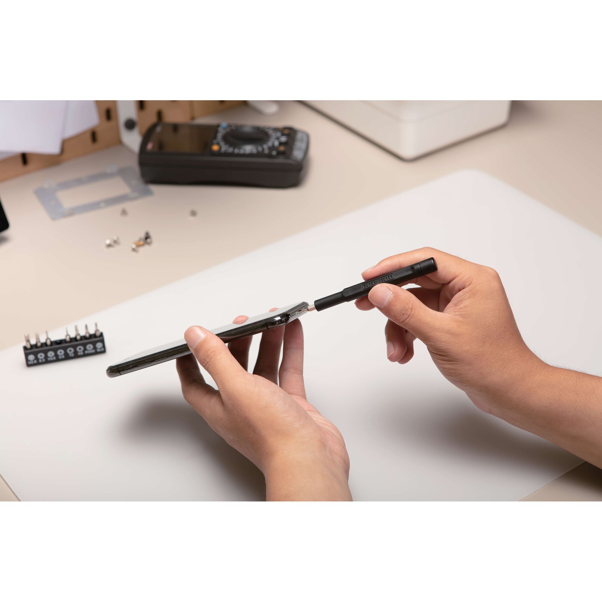 BLACKDECKER BD40K27 precision screwdriver set used to open a smartphone, photography at desktop angle.