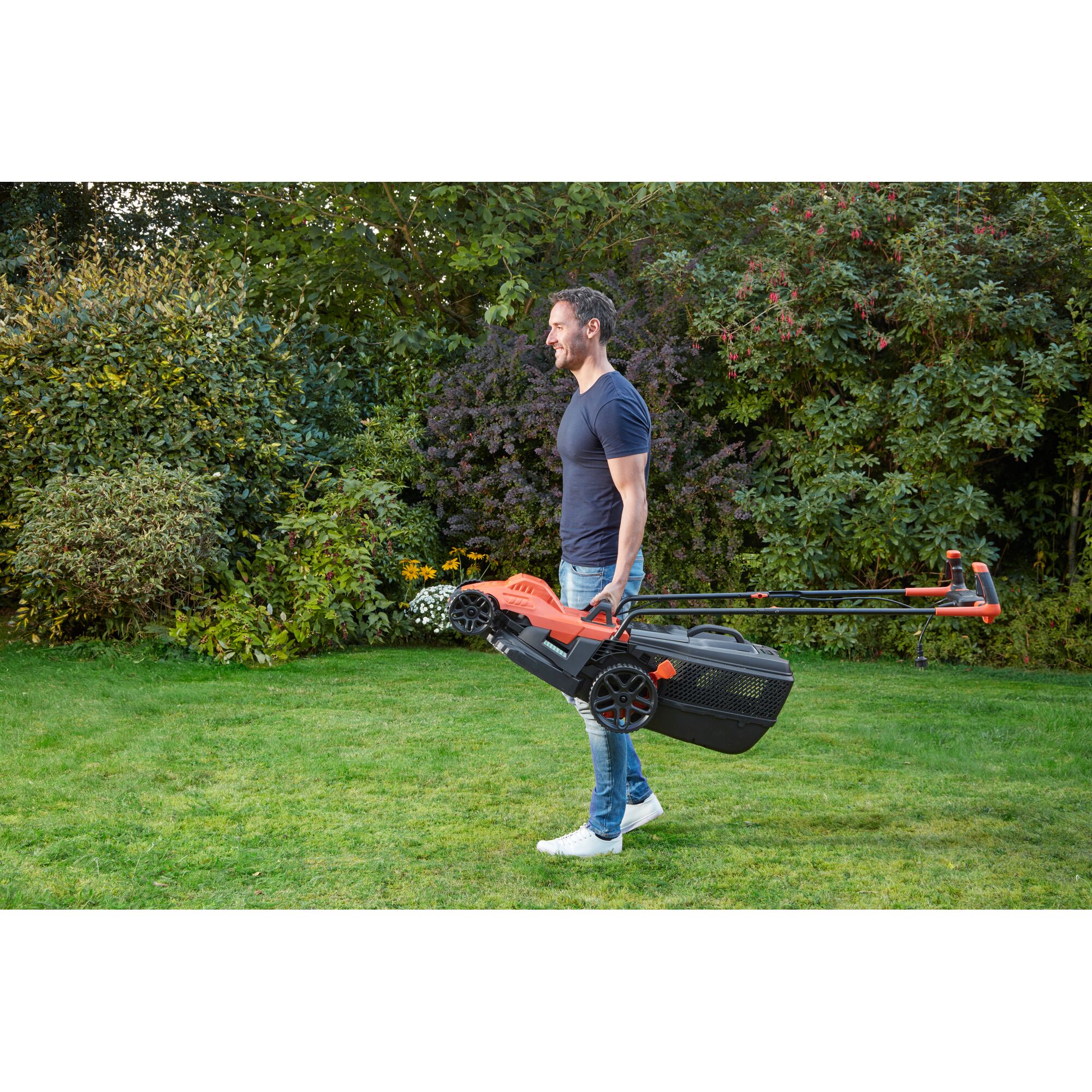 BLACKDECKER BEMW471BH lawn mower carried by person in garden setting.