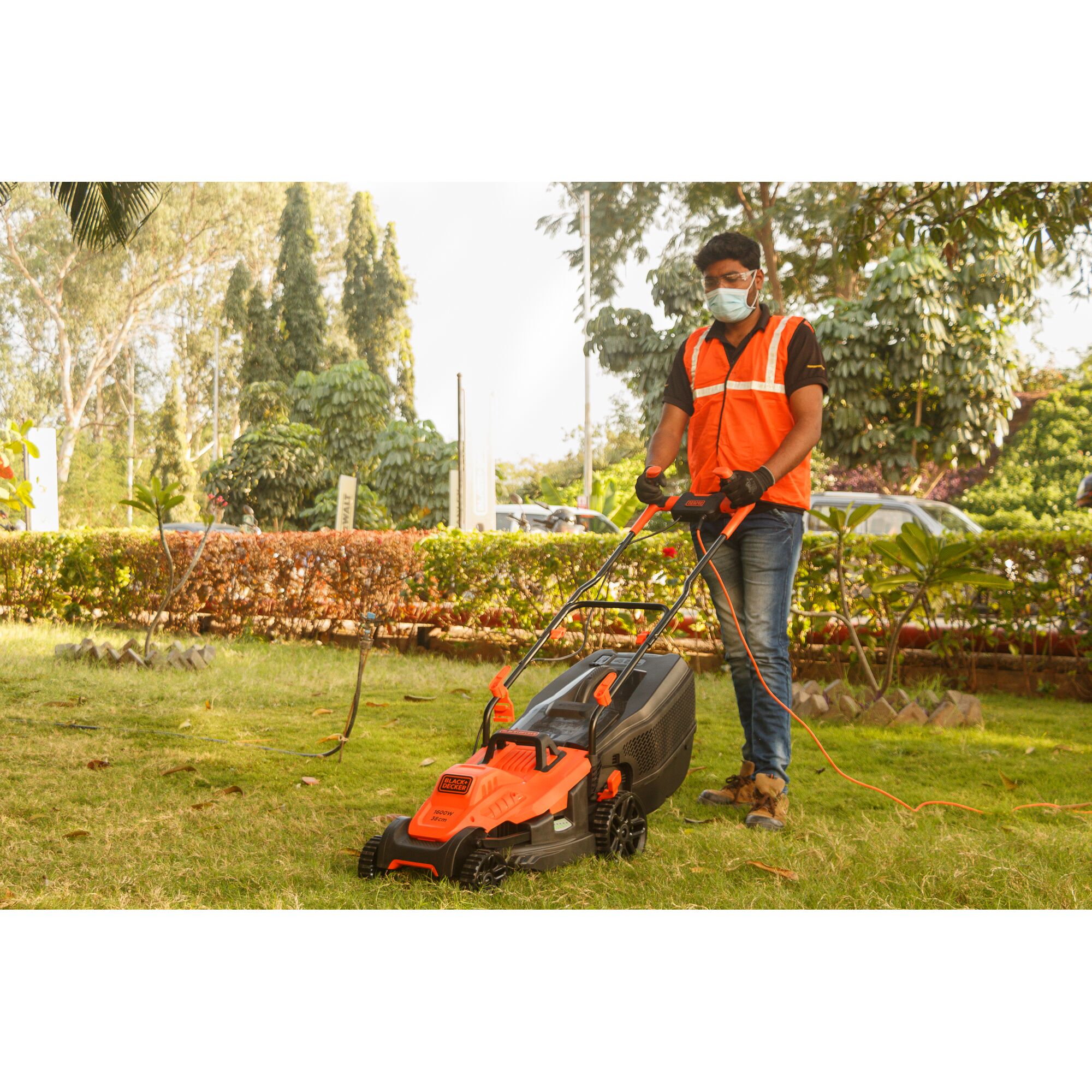 BLACKDECKER BEMW471BH electric lawn mower with grass collection bag in use on a grassy lawn, front side view.