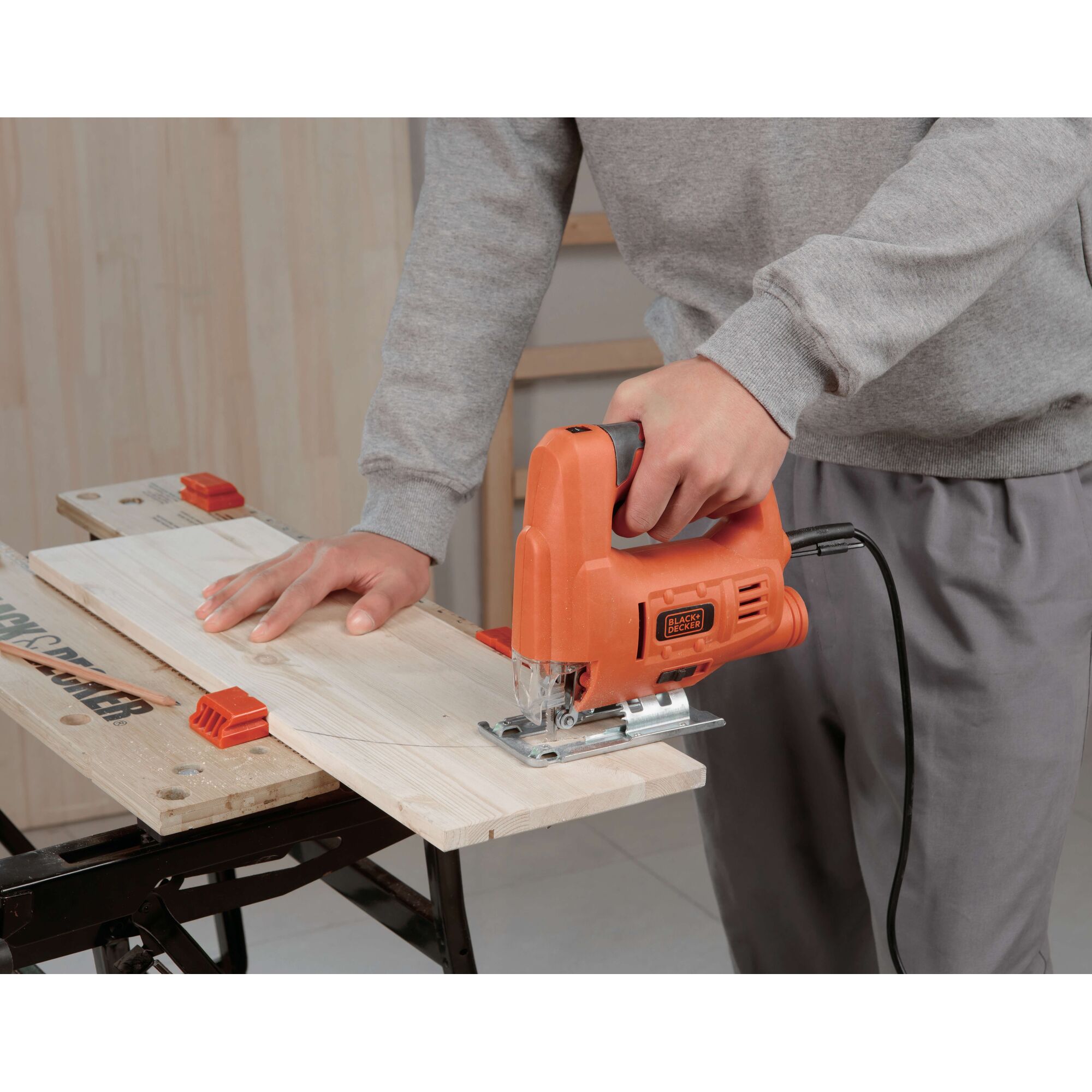 BLACKDECKER JS20 jigsaw cutting wood on workbench, close-up of tool in use.