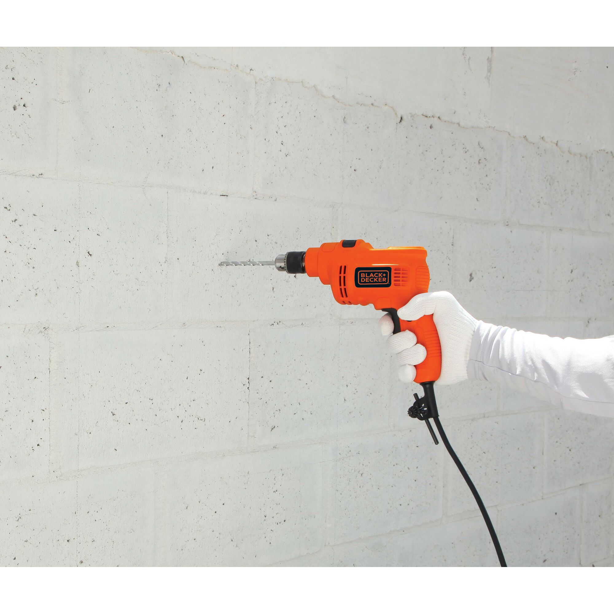 BLACKDECKER KR5010 orange corded drill held against white concrete wall, side view, power tool category.