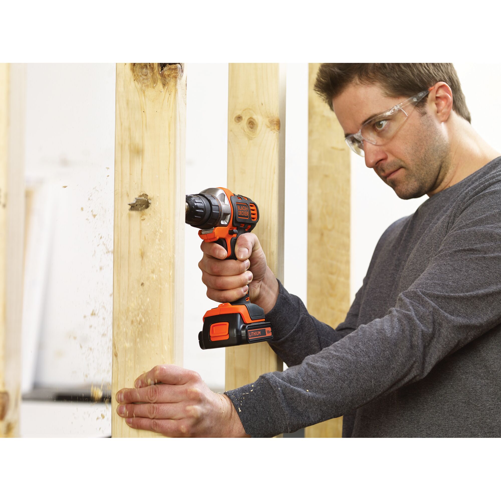 Photo of BLACKDECKER MT218K cordless drill in use, drilling through wood framing.