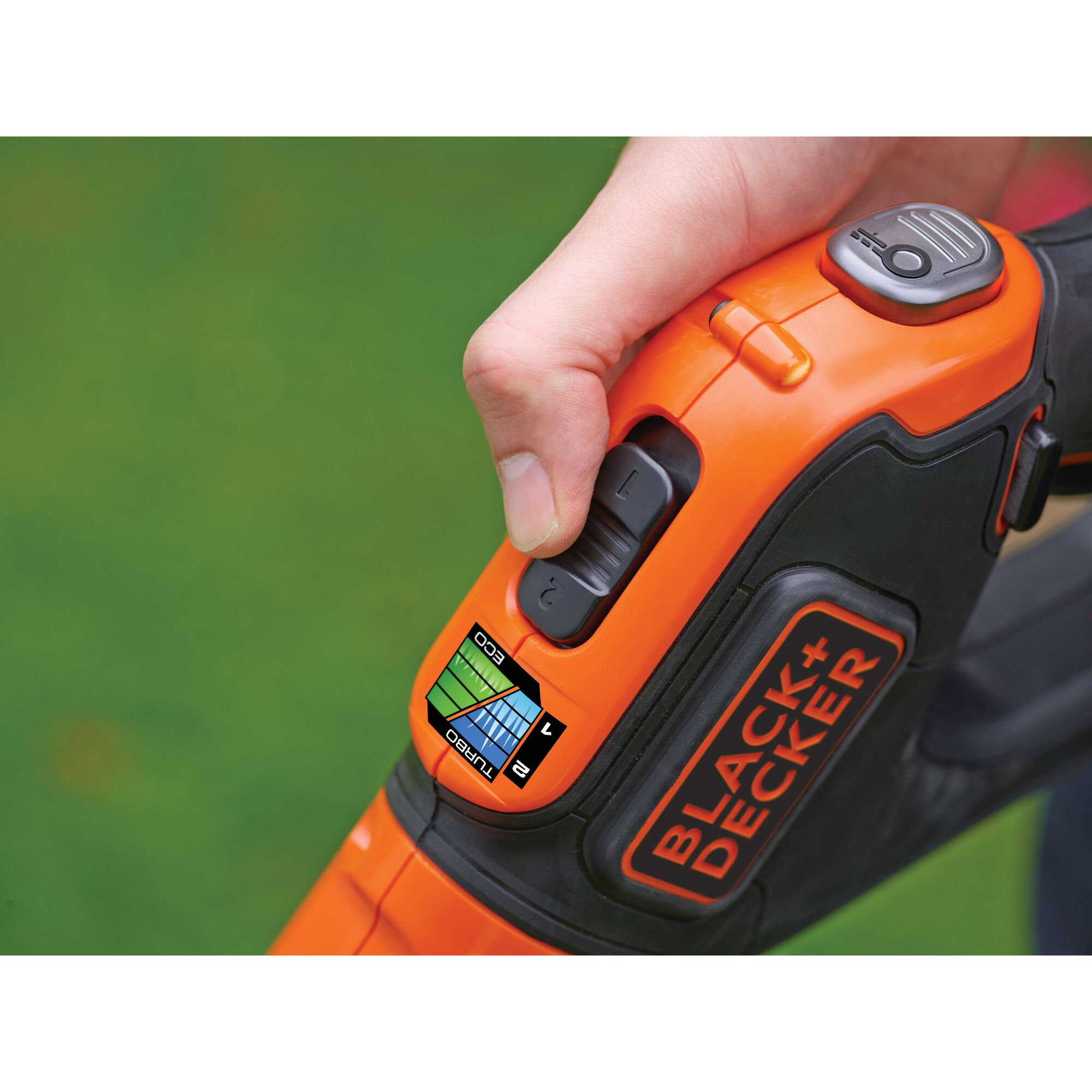 Close-up of a hand adjusting the power settings on an orange and black BLACK+DECKER garden tool, showing labeled buttons and the brand logo.